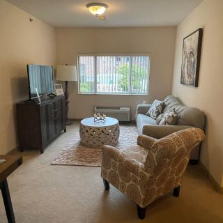 A cozy living room with a sofa, armchair, and television.