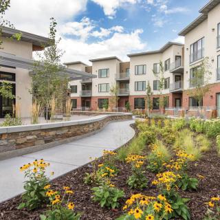 A modern apartment complex with well-maintained gardens and a winding pathway.