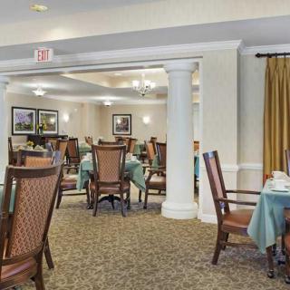 A spacious dining room with elegantly set tables and chairs, featuring a warm and inviting atmosphere.
