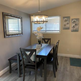 A cozy dining room with a dark wood dining set, elegant chandelier, and tasteful wall decorations.