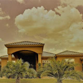 A beautiful residential building surrounded by lush greenery and a dramatic sky.