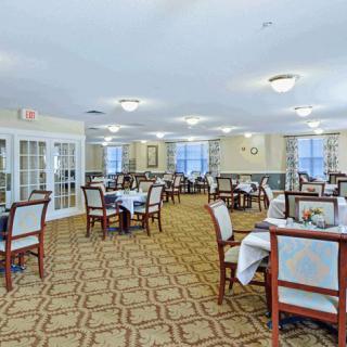 A spacious dining room with neatly arranged tables and chairs, featuring elegant decor and ample lighting.