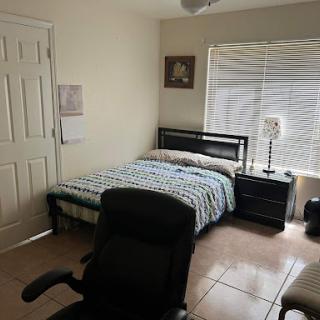 A cozy bedroom featuring a bed, nightstand, and a comfortable chair.