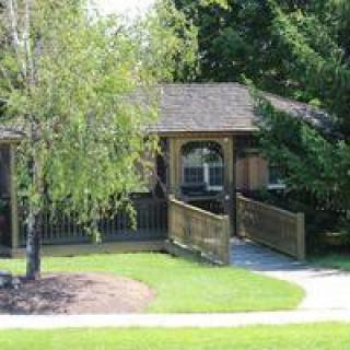 A small house surrounded by greenery with a walkway leading to the entrance.