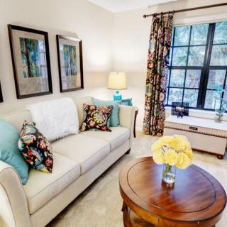A cozy living room with a beige sofa, colorful cushions, and decorative artwork on the walls.