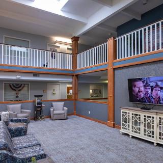 A spacious two-story living area with comfortable seating, a large television, and natural light from a skylight.