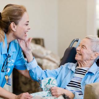 A nurse interacts warmly with an elderly patient, sharing smiles and care.