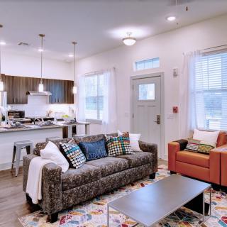 A modern living room with an open kitchen view, featuring a comfortable sofa, armchair, and stylish decor.
