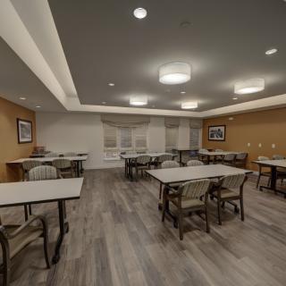 A spacious meeting room with multiple tables and chairs arranged under bright lighting.