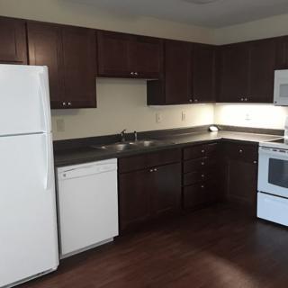A modern kitchen with dark wood cabinets and white appliances.