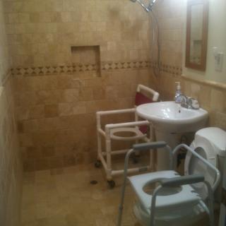 A handicap-accessible bathroom with tiled walls, equipped with a sink, toilet, and grab bars.