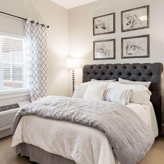 A cozy bedroom with a plush bed, elegant artwork, and soft lighting.