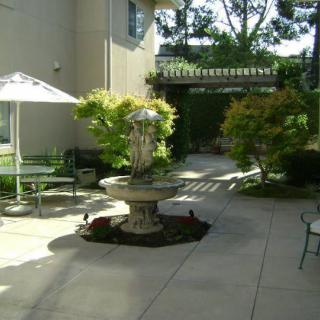 A serene courtyard with a central fountain, surrounded by greenery and outdoor seating.