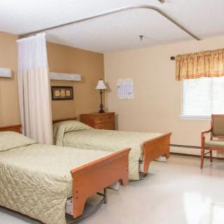 A hospital room with two beds, curtains for privacy, and a window providing natural light.