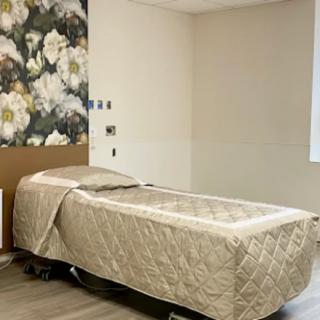A tranquil spa room with a massage table and floral wallpaper.
