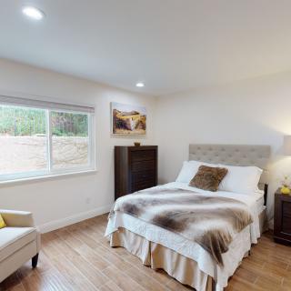 A cozy bedroom with modern decor, featuring a bed, chair, and window.