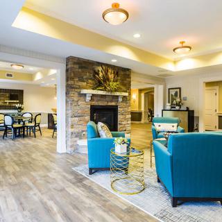 A modern living room with teal armchairs, a stone fireplace, and warm lighting.