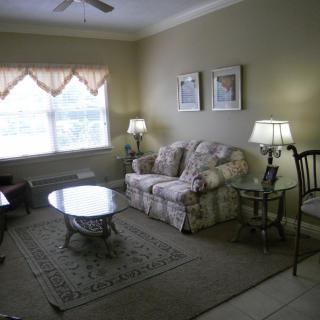 A cozy living room with a sofa, coffee table, lamps, and artwork on the wall.