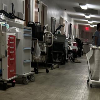 A busy hospital corridor lined with various medical equipment and trolleys.