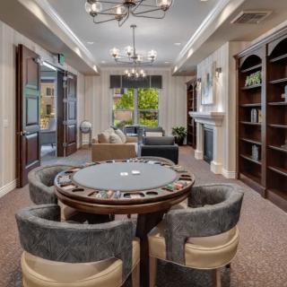 A modern living room with elegant furnishings, featuring a round table surrounded by chairs and large bookshelves.