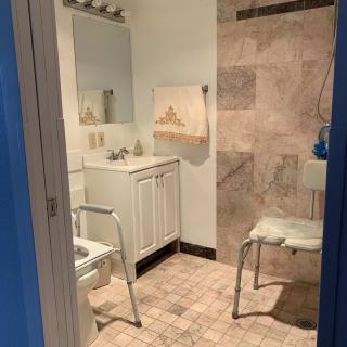 An accessible bathroom with safety features including a shower chair and handrails.
