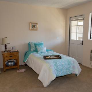 A cozy bedroom with a single bed, nightstand, and lamp.