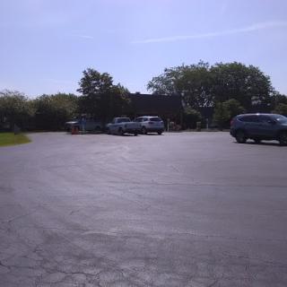 A quiet parking lot with several cars parked under a clear blue sky.