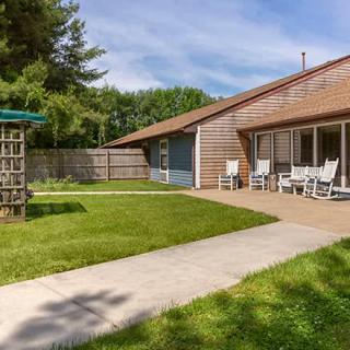 A cozy backyard with a well-maintained lawn and a patio area featuring outdoor seating.