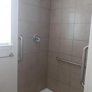 A tiled bathroom shower with grab bars installed.