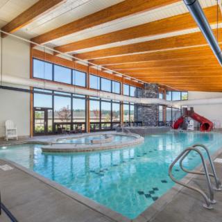An indoor pool with a water slide, featuring large windows and modern architectural design.