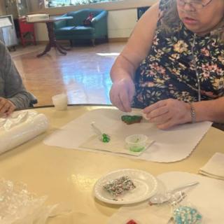A person engaged in a crafting workshop, carefully working with materials at a table.