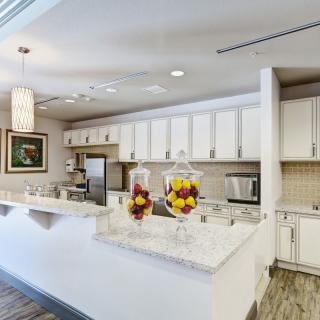A modern kitchen with white cabinets and sleek countertops, featuring decorative elements and appliances.