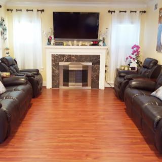A cozy living room with leather sofas, a mounted TV above the fireplace, and hardwood flooring.