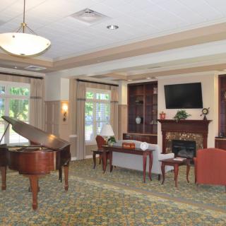 A cozy living room featuring a grand piano, fireplace, and comfortable seating arrangements.