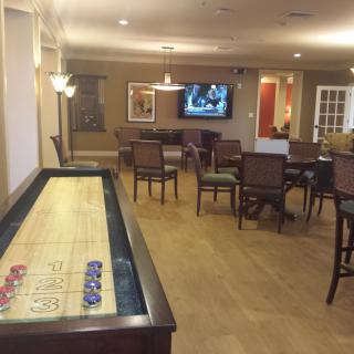 A game room featuring a shuffleboard table and a television with seating area.