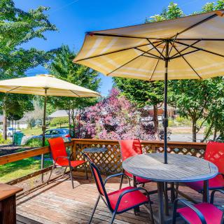 A sunny outdoor patio with tables and umbrellas surrounded by greenery.