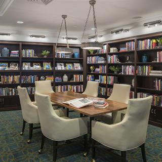 A cozy reading room with shelves full of books and comfortable seating around a central table.