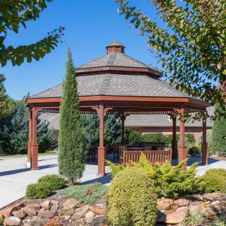 A beautiful wooden gazebo surrounded by greenery in a landscaped garden.