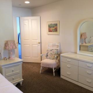 A cozy bedroom with white furniture and decor.