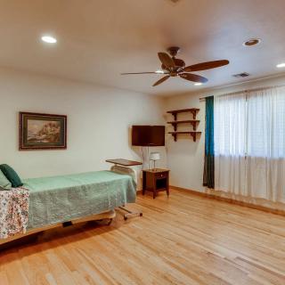 A cozy bedroom with a single bed, wooden floors, and a ceiling fan.