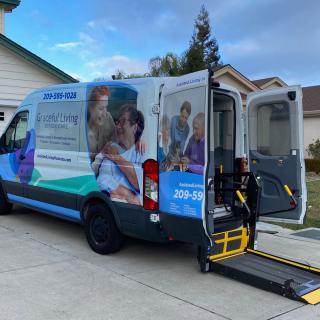 A healthcare service van equipped with an accessibility ramp parked in a residential area.