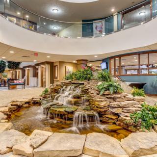 A modern lobby featuring an indoor waterfall surrounded by plants and elegant decor.