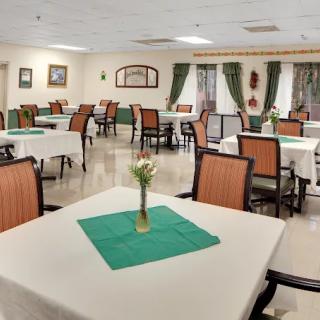 A well-arranged dining room with neatly set tables and chairs, featuring decorative flowers on each table.