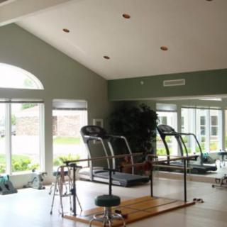 A spacious gym interior featuring treadmills and fitness equipment with large windows providing natural light.
