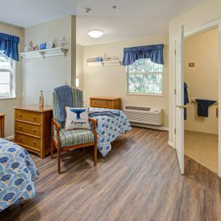 A cozy bedroom with two beds, a dresser, and a chair by the window.