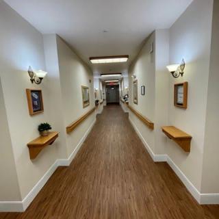 A well-lit hallway with wooden floors and decorative pictures on the walls.