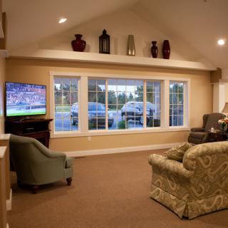 A cozy living room featuring a large window, comfortable seating, and a television.