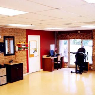A modern office space with desks, chairs, and a computer set against a brick wall backdrop.