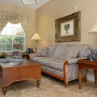 A cozy living room with a sofa, coffee table, lamps, and wall art.