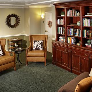 A cozy living room with armchairs and a well-stocked bookshelf.